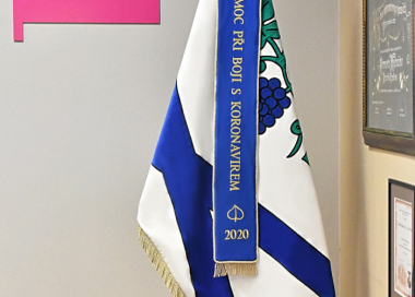 Vyšívaná stuha modrá s děkovným textem „Za pomoc při boji“ vyvěšena na slavnostní obecní vlajce