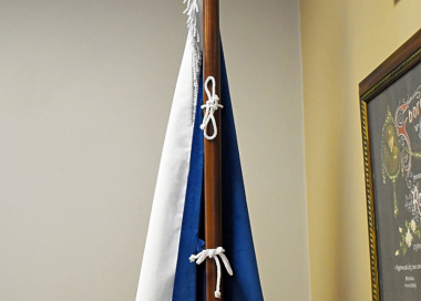 Uchycení sametové vlajky ČR na jednodílné žerdi přes ozdobné kroucené šňůrky provlečené poutky všitými v praporu
