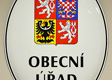 Bílý smaltovaný ovál se státním znakem České republiky a nápisem OBECNÍ ÚŘAD