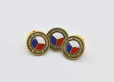 Odznak je vyplněn barevnou stylizovanou českou vlajkou.