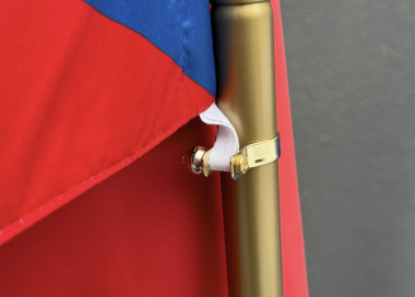 Detail uchycení interiérové tištěné vlajky pomocí poutek na stojanu.